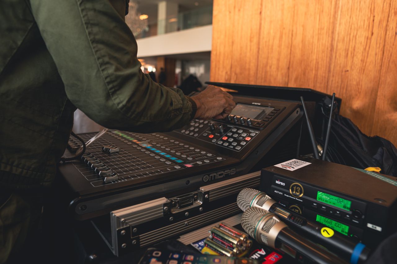 A sound engineer at work adjusting an audio mixer indoors, captured in detail.